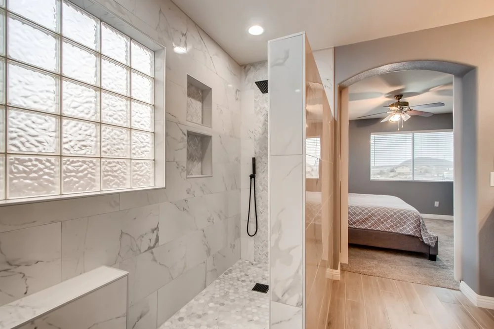 Bright walk-in shower with white tile and a glass-block window