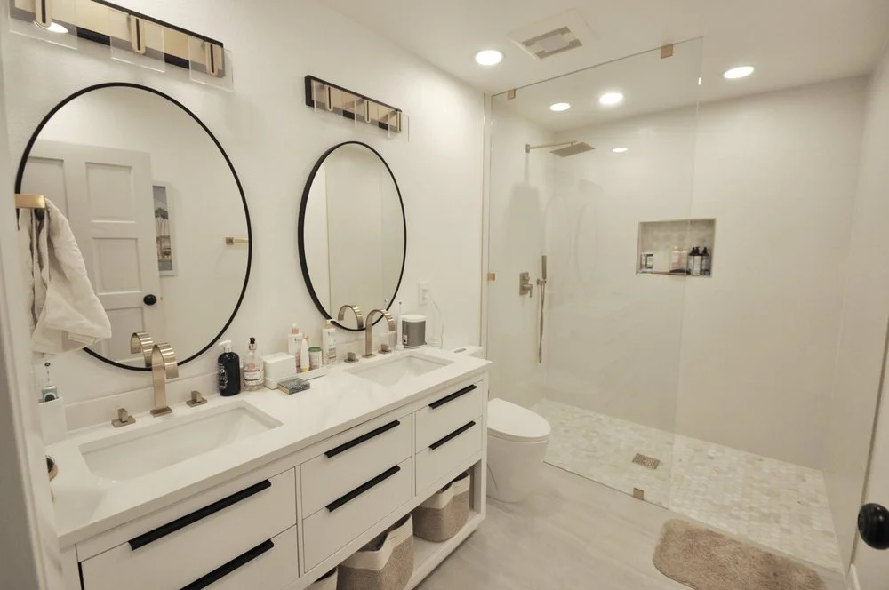 White double vanity with round mirrors and black cabinet hardware